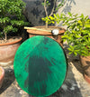 Green drum in front of potted plants
